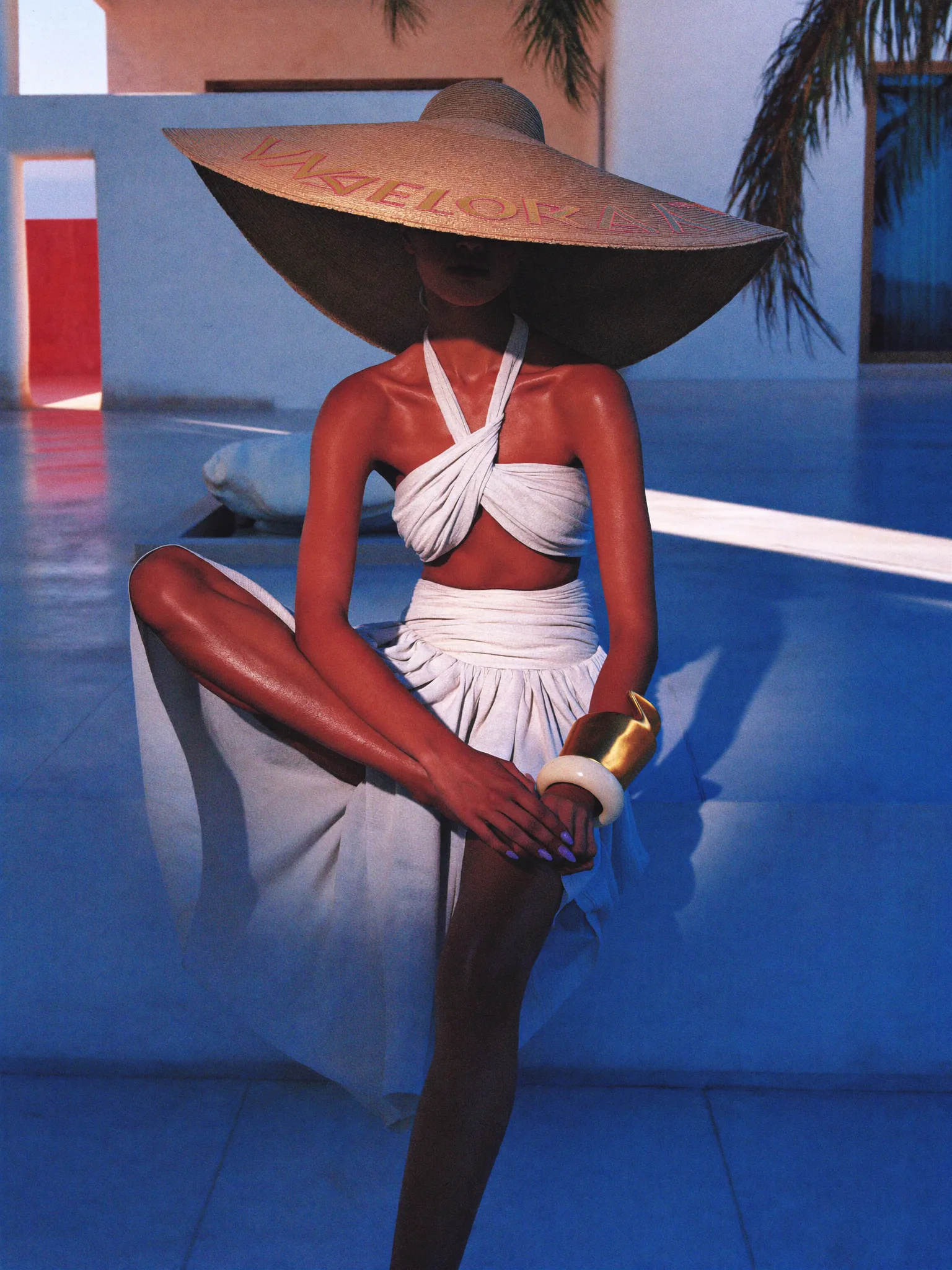 Portrait in a wide-brimmed hat by a blue pool